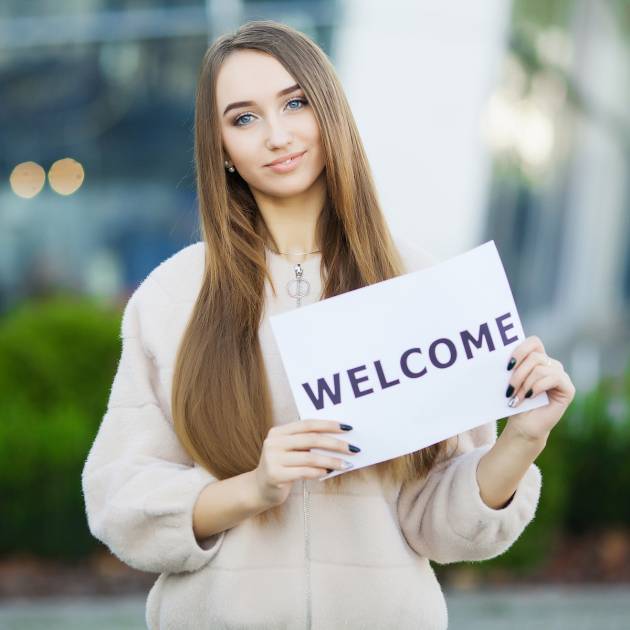 Businesswoman with long Hair Holding a sign Board with a Welcome has Airport Background.