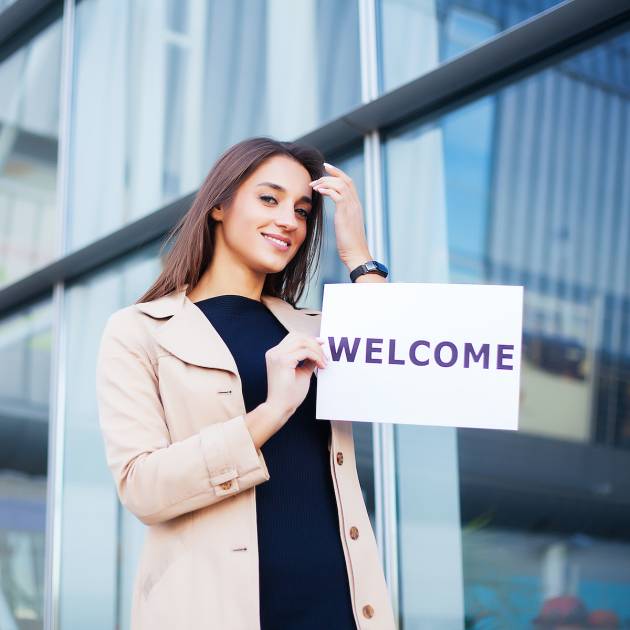 Women business with the poster with welcome message.