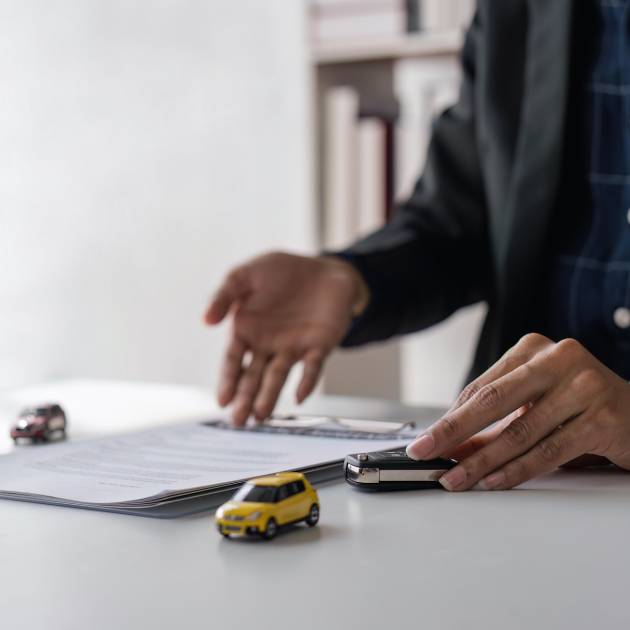 signing car insurance document or lease paper. Writing signature on contract or agreement. Buying or selling new or used vehicle. Car keys on table. Warranty or guarantee. Customer or salesman.
