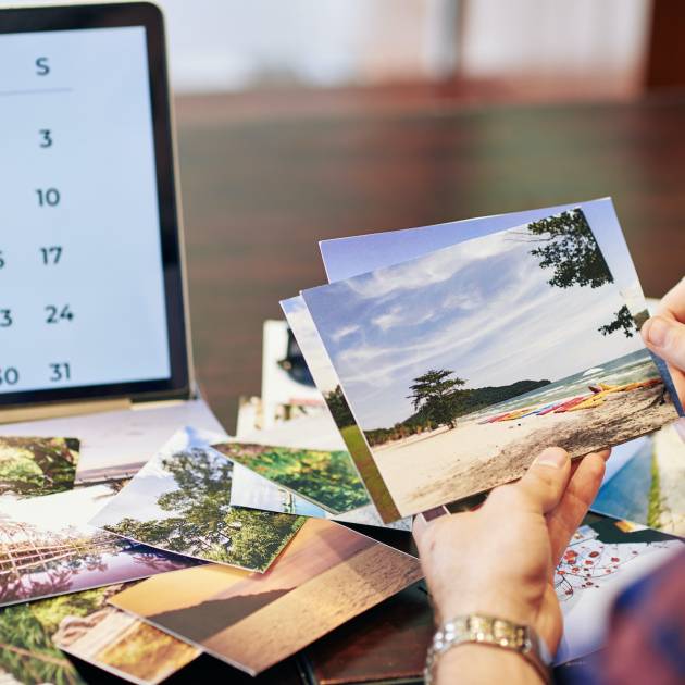 Hands of traveler checking photos he printed after summer vacation