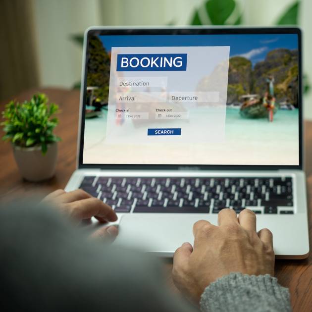 Online booking platform on a laptop computer by a person. Man use websites to search for accommodation, hotels and airlines for their vacation trips or buy tours on the Internet.