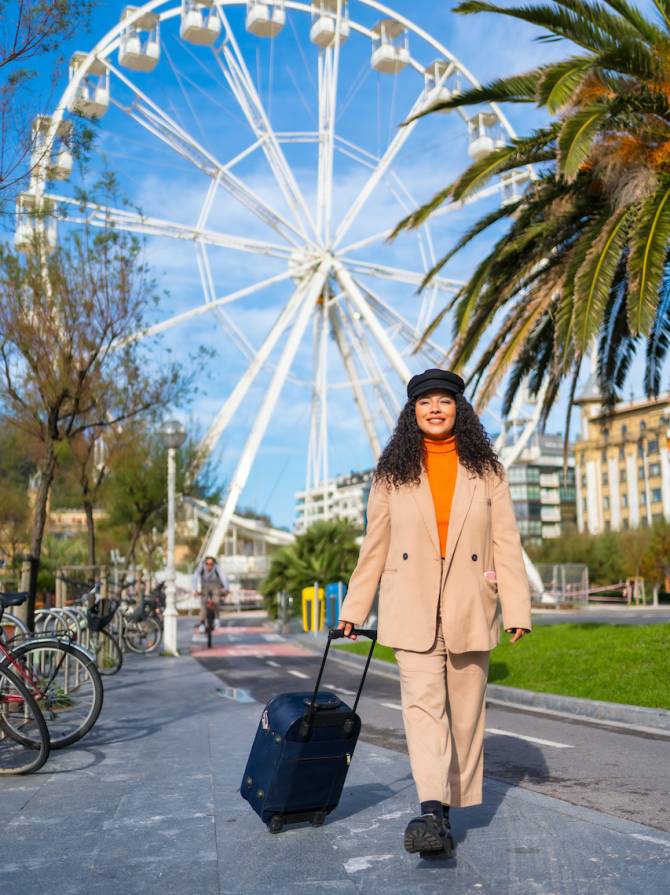 Vertical photo of a chic latin tourist arriving at a city with a Ferris wheel