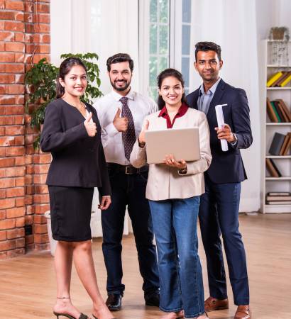 Indian asian business people or business corporate colleagues discussing work on a laptop while standing in posh office